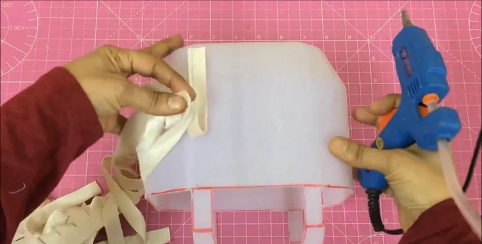 Begin weaving the contrasting strips, pulling one up and two down, fixing them to the basket.