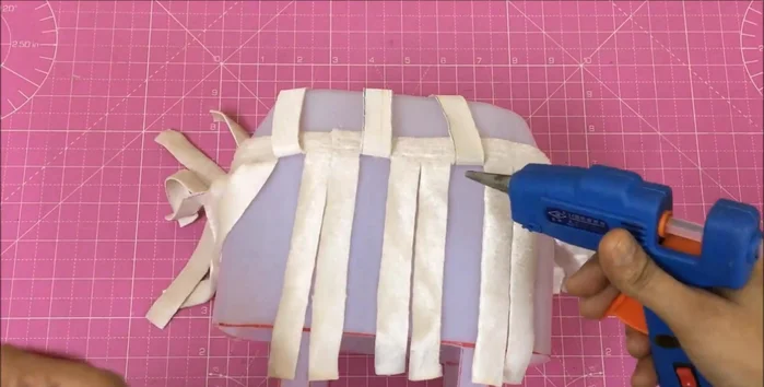 Begin weaving the contrasting strips, pulling one up and two down, fixing them to the basket.