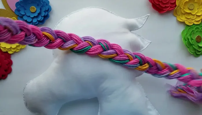Glue the wool pieces onto the felt unicorn face to create the mane and tail.