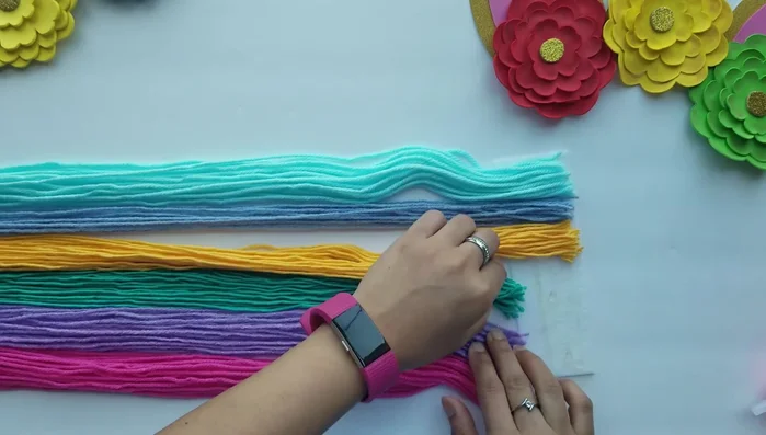 Glue the wool pieces onto the felt unicorn face to create the mane and tail.