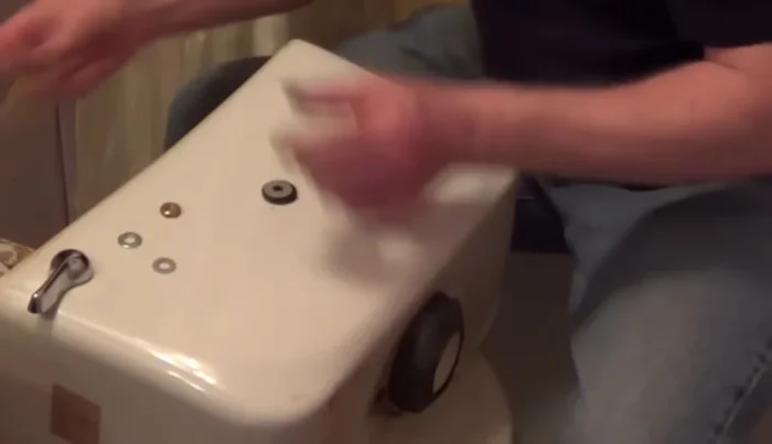 Replace the tank onto the bowl and secure it from underneath, ensuring even tightening of nuts with a helper.