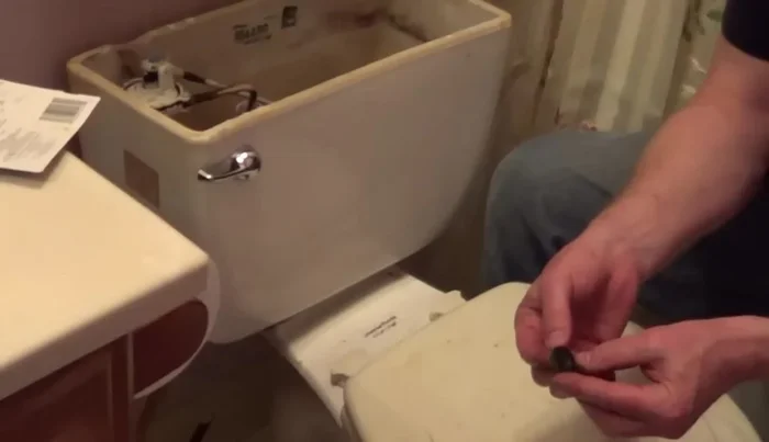 Replace the tank onto the bowl and secure it from underneath, ensuring even tightening of nuts with a helper.