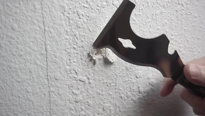 Carefully remove the excess drywall using a knife, creating a clean, recessed area around the nail or screw.