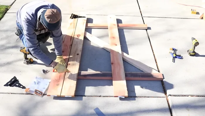 Attach hinges to the gate. Mark the center using a speed square, pre-drill, then attach using lag bolts. Only use center bolt temporarily to hold while checking fit.