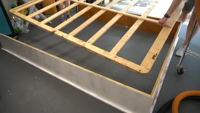 Attach base to frame: With the frame upside down, attach the prepared box spring base using wood glue, clamps, and brads.