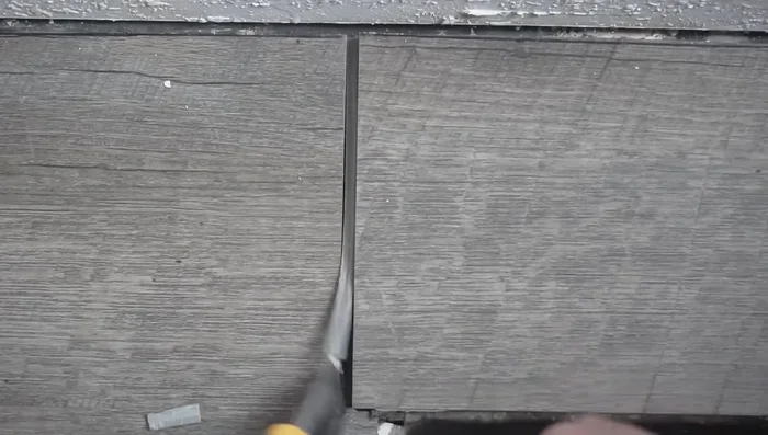 Carefully remove the damaged plank using a utility knife or other prying tools.