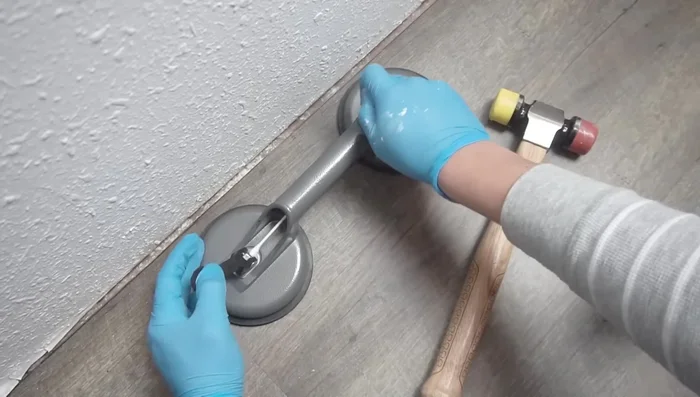 Insert the replacement plank into the gap and tap it into place using a mallet and suction cup.