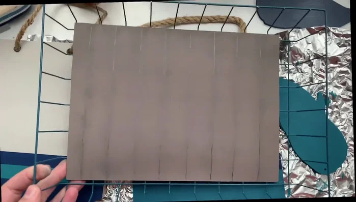 Creating a rustic look on a Target dollar spot wooden board using a ruler, pencil, and finger to rough up the paint.