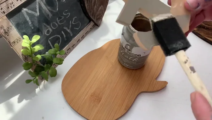 Creating a fishnet decor piece using Dollar Tree seashells and hot glue.