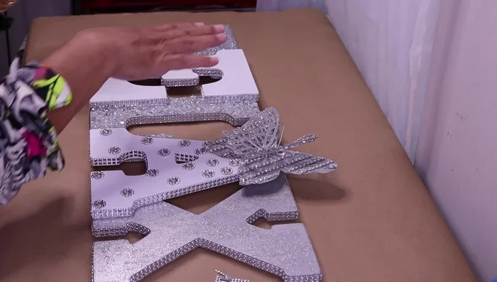 Decorate the letter 'E' with strips of silver bling and small rectangular bling pieces and crowns.