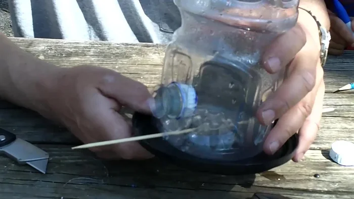 Cut the top off the plastic coffee can and center it on the soda bottle, securing it with screws.