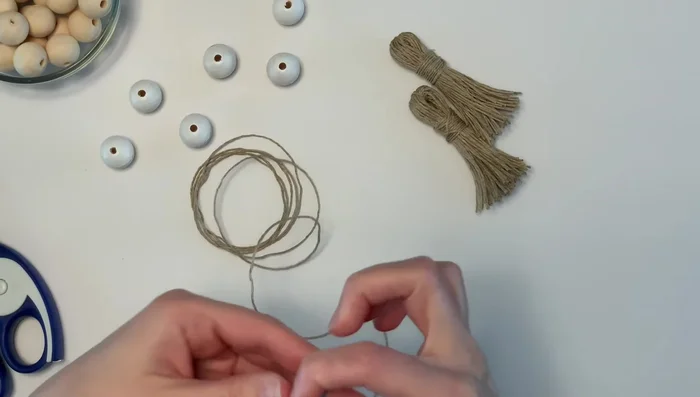 Prepare twine for bead stringing: Cut a two-foot-long piece of twine. Optionally, apply painter's tape to the end and cut it into a triangle to help with stringing.