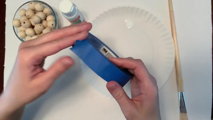 Prepare beads: Cover half of six beads with blue painter's tape, leaving the other half exposed for painting.