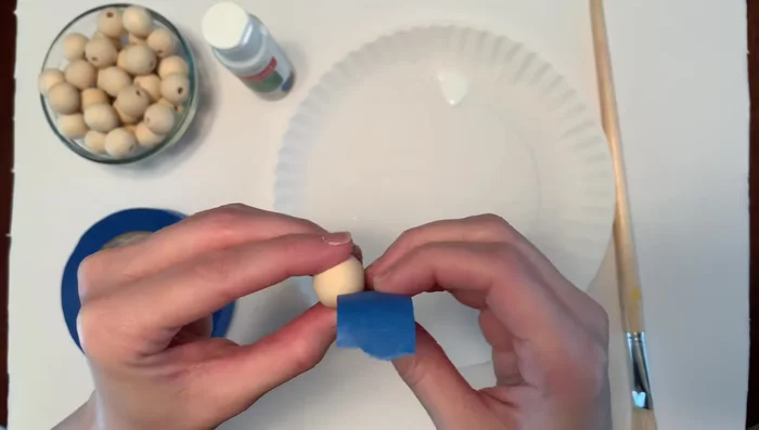 Paint beads: Paint the exposed half of the taped beads white and let them dry for about 30 minutes.