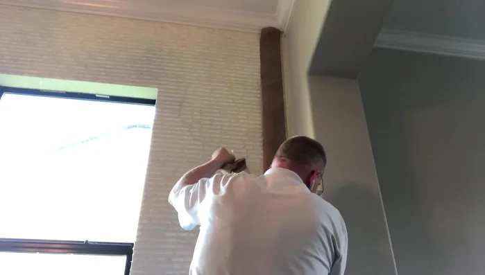 Carefully remove the masking tape while holding the wallpaper to prevent damage. Peel from the bottom up, keeping your finger under the tape to avoid pulling on the wallpaper.