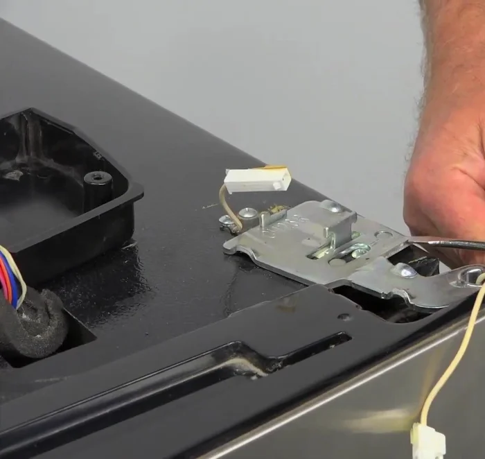 Remove the duct tape from the door and carefully remove the door from the refrigerator, ensuring all shelves are emptied beforehand.