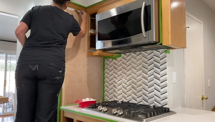 Lightly sand the primed cabinets to smooth any texture.