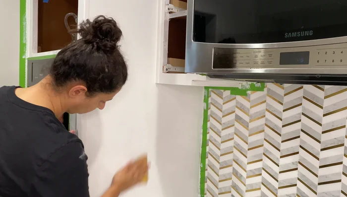 Lightly sand the primed cabinets to smooth any texture.