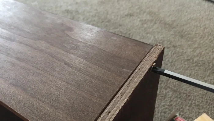 Screw the repair piece to the drawer back, ensuring it's flush with the existing surface. Drill from the back into the repair piece to add screws.