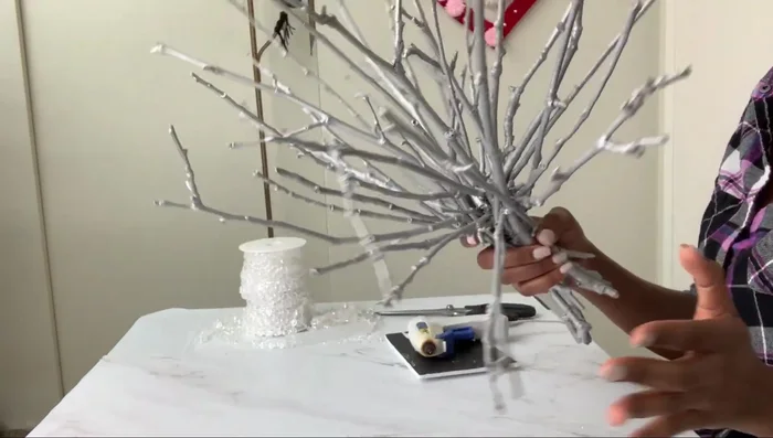 Create the base: Fill the base of the branch structure with white stone pebbles for stability.