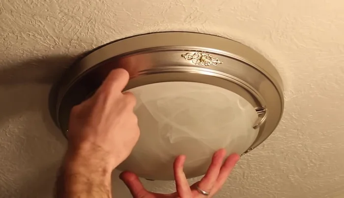Use blue tape to secure the old fixture to the ceiling while lowering it.