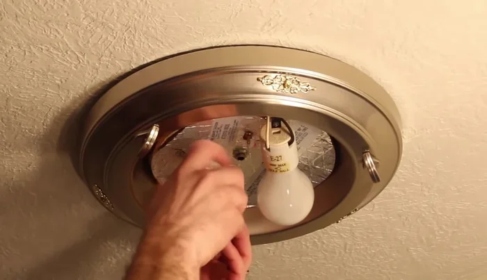 Use blue tape to secure the old fixture to the ceiling while lowering it.