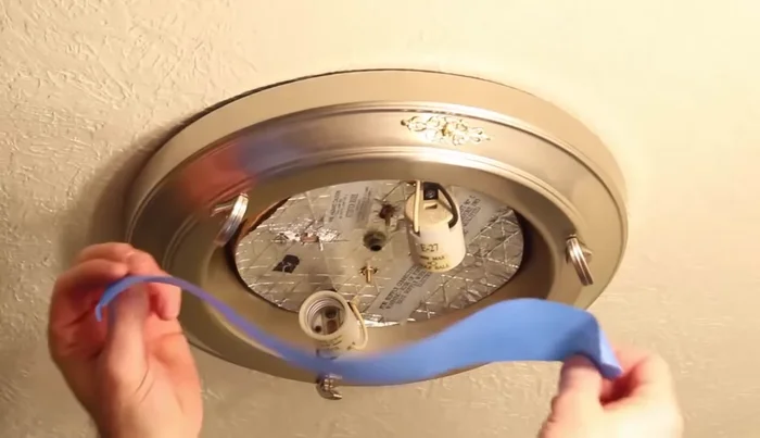 Use blue tape to secure the old fixture to the ceiling while lowering it.
