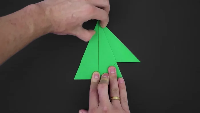 Fold the remaining flaps, unfold, and turn over. Fold the middle triangle in half by bringing the top corner down to the edge.