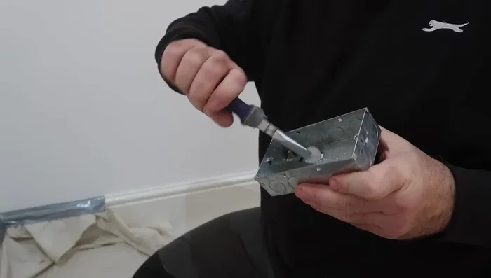 Use a chisel to carefully remove excess brick material around the hole to create a recess for the back box.