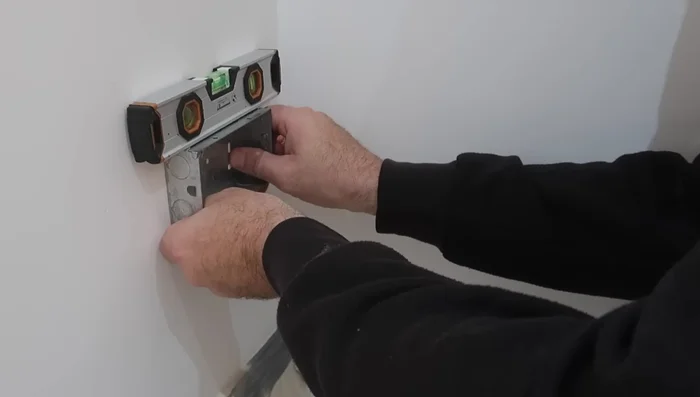 Use a chisel to carefully remove excess brick material around the hole to create a recess for the back box.