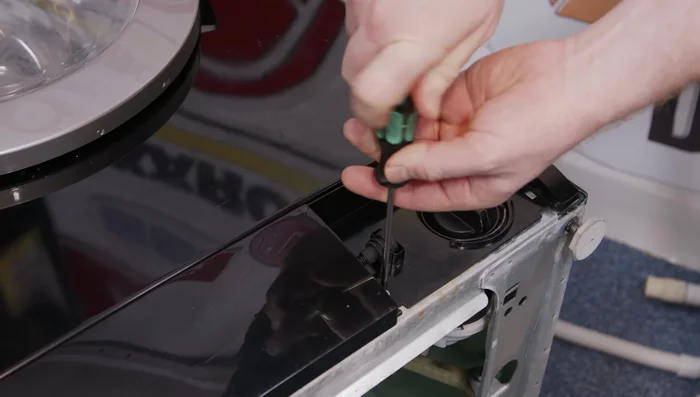 Unscrew the Torx head screw holding the pump chamber and tilt it back to access the drain hose.