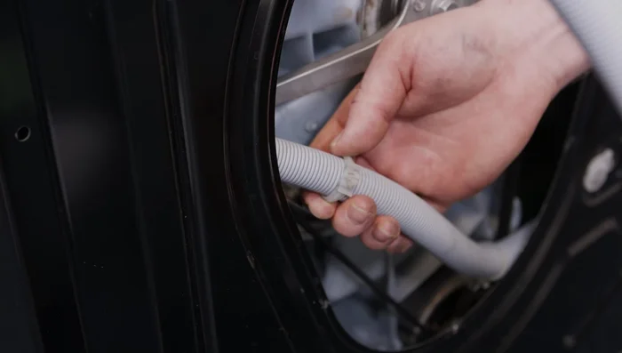 Refit the kick panel, making sure to route the emergency drain hose correctly and secure the clips.