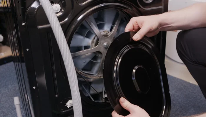 Refit the kick panel, making sure to route the emergency drain hose correctly and secure the clips.