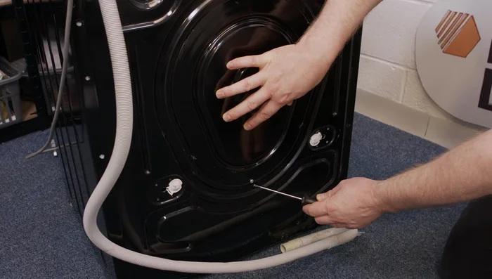 Unscrew the Torx head screw holding the pump chamber and tilt it back to access the drain hose.