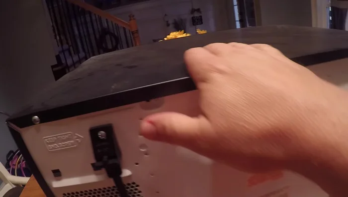 Carefully remove the top cover of the microwave to access the internal components. Be cautious of the high-voltage capacitor; if unsure, discharge it safely using an insulated screwdriver.