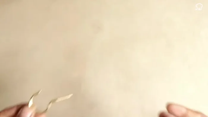 Attach the metal hook: Thread the metal hook through the bottom of the larger bottle