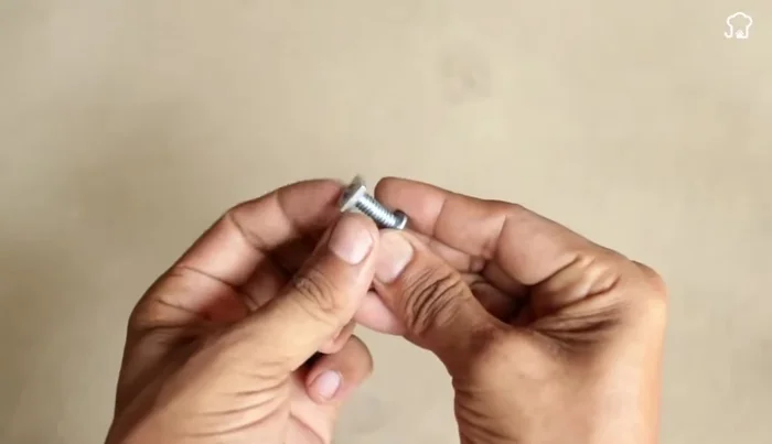 Attach the smaller bottle: Thread the cut plastic piece from the smaller bottle onto the screw and add another washer