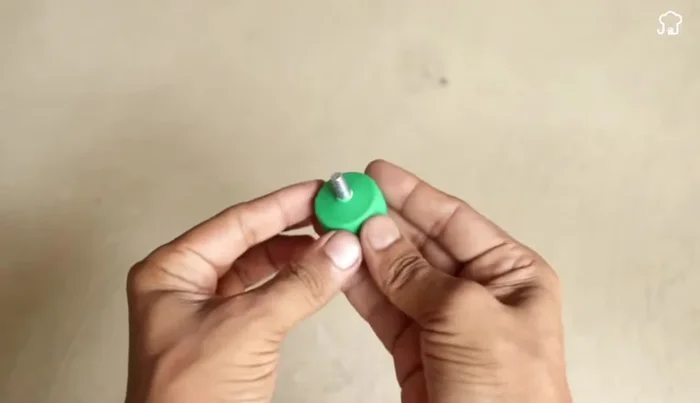 Attach the smaller bottle: Thread the cut plastic piece from the smaller bottle onto the screw and add another washer