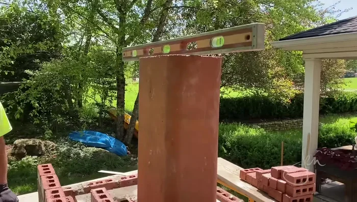 Install the flue liner: Place the flue liner above the firebox and fill the surrounding space with blocks and bricks.