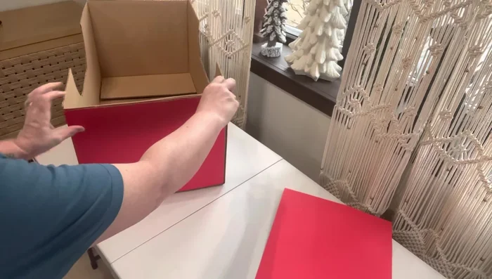 Assemble the car body: Hot glue the red poster board onto the front and back of the cardboard structure, then attach the side pieces. Trim excess poster board.