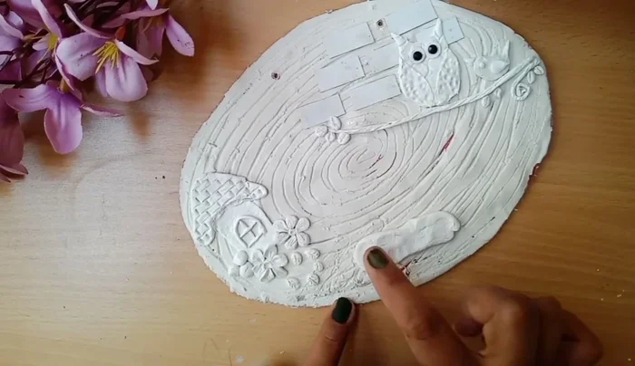 Roll out clay and spread it on the board. Use a tool for texture.