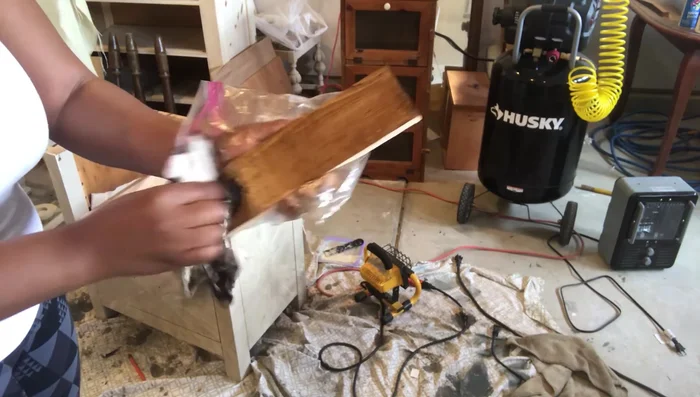 Attach the stained wooden planks to the dresser using a nail gun.