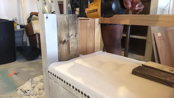 Attach the stained wooden planks to the dresser using a nail gun.