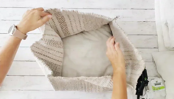 Stuff the pouf with six throw pillows. One side remains open while working on the other.