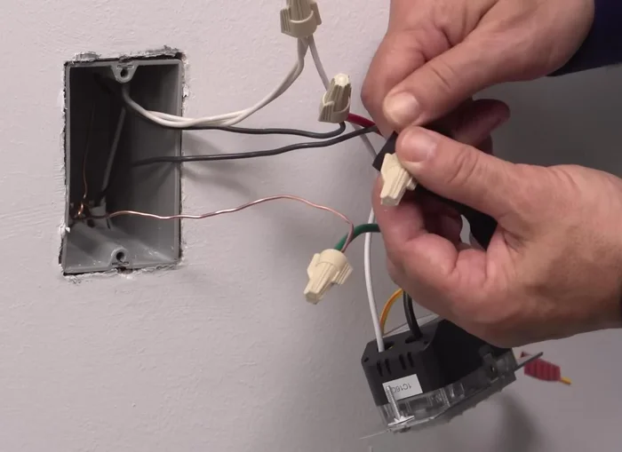 Position all wires in the wall box, ensuring the word "top" is facing up on the device. Partially screw in the mounting screws.