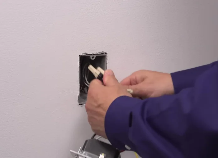 Position all wires in the wall box, ensuring the word "top" is facing up on the device. Partially screw in the mounting screws.