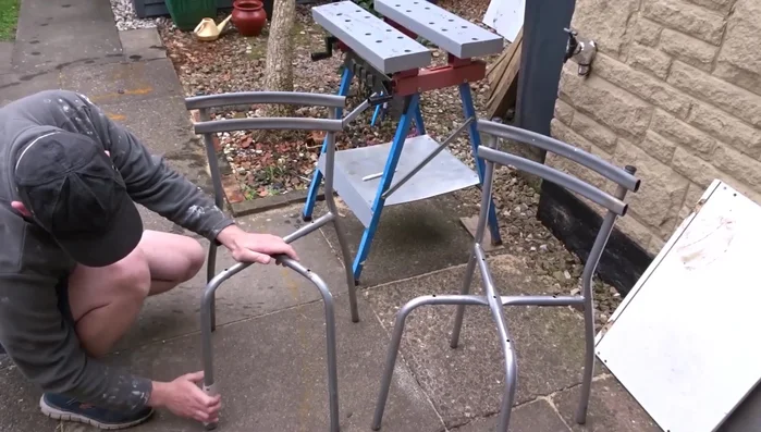 Lightly sand the metal chair frames to prepare for painting. Remove dust with a cloth.