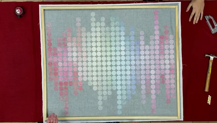 Staple the top and bottom edges of the fabric to the frame, stretching the fabric evenly. Tuck the corners to create a neat finish and staple them securely.