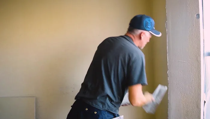 Apply a first coat of mud, ensuring full coverage of the tape. Check for any protruding nails or other imperfections and address them.