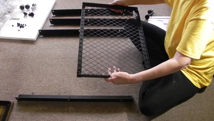 Securing shelves and top: Insert screws through the holes in the side braces and into the shelves and top. Start screws by hand, then tighten with a wrench or hex key. Ensure screws are straight before fully tightening.